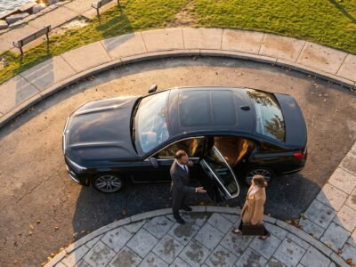 Chauffeur welcoming an executive passenger beside a luxury saloon for the best Pickering Pearson limo transfer outside an upscale waterfront district.