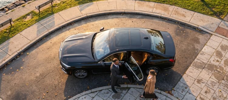 Chauffeur welcoming an executive passenger beside a luxury saloon for the best Pickering Pearson limo transfer outside an upscale waterfront district.